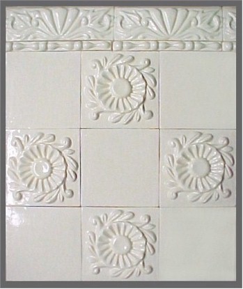 handmade wall demonstration of ceramic tiles with high relief floral designs and trim tiles, all with a  one color glaze